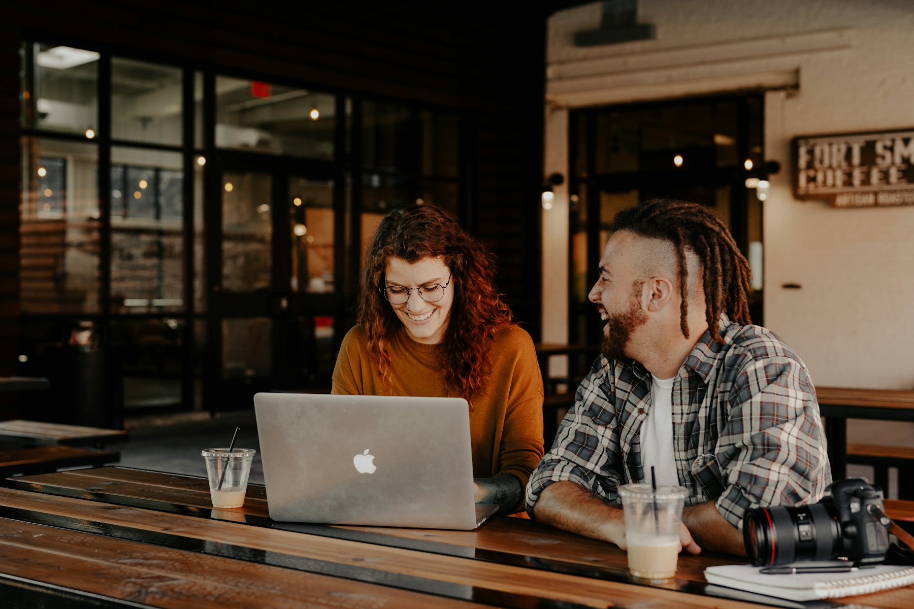 Two people sharing a conversation over a laptop and coffee